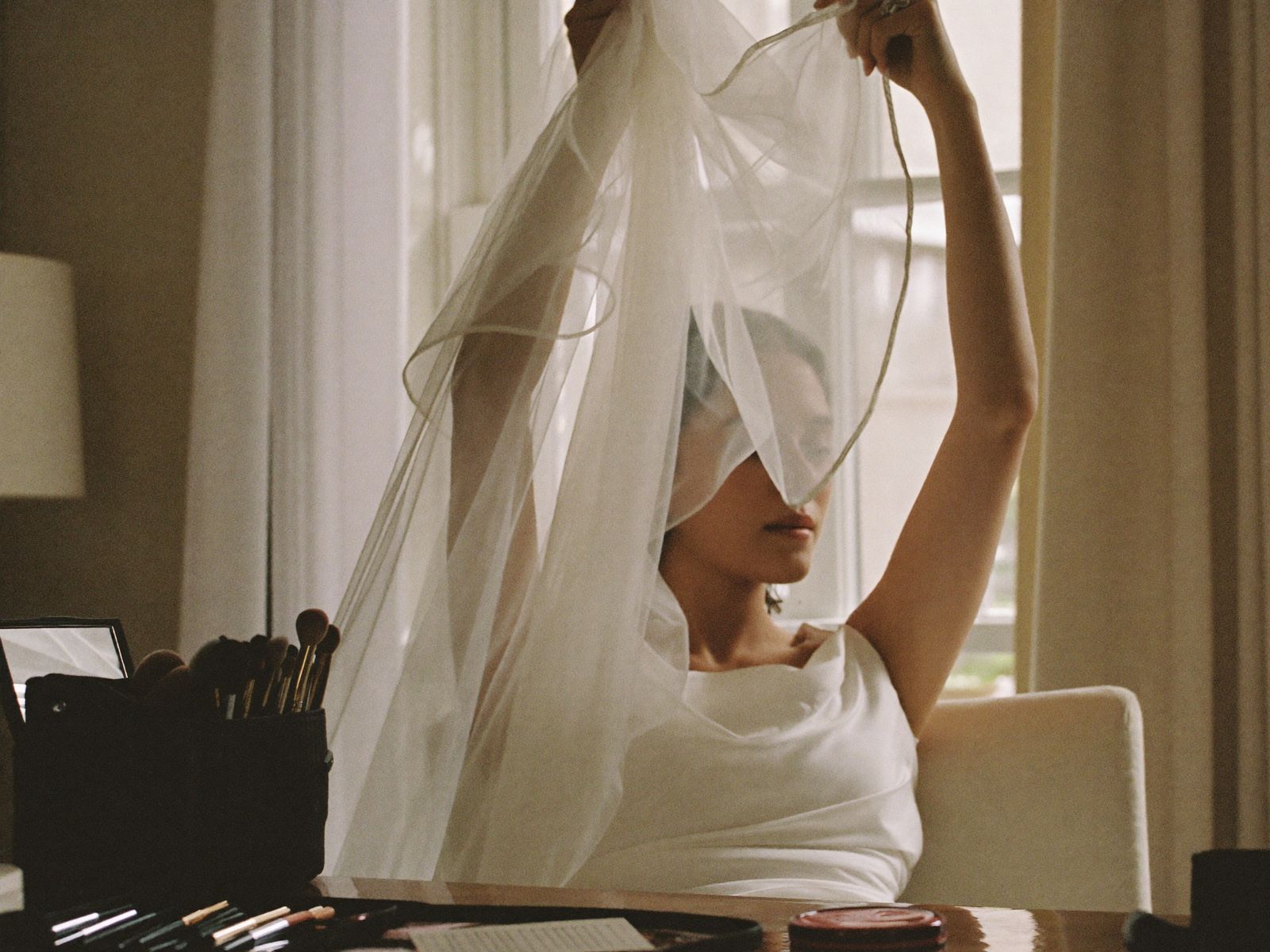 A bride lifting her veil in soft morning light